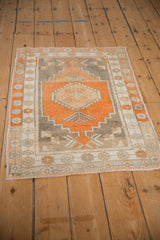 Angled view of a vintage distressed Oushak rug in terracotta and silver tones.