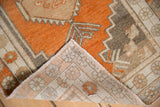 Folded corner of a distressed Oushak rug revealing the hand-knotted reverse side.