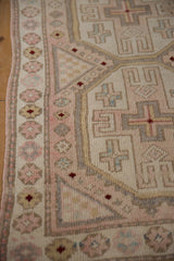 Vintage Oushak rug detail with pale rose blossoms, soft distressed pile, and geometric patterns.