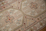 Distressed Oushak rug detail showing pale rose, ivory, and blue geometric blocks.