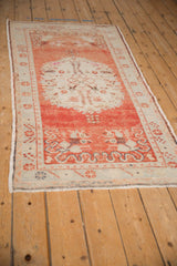 Angled view of a distressed Oushak runner, showing the full length of its brick red and ivory medallion design.