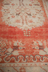 A close view of the distressed vintage Oushak rug's low pile and time-softened brick red color.