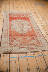 Angled view of a vintage Oushak runner with an abrashed brick red field and a large ivory medallion.