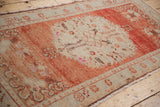 Angled view of a distressed Oushak runner's worn pile with brick red and pale ivory hues.