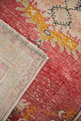 Distressed cherry red Oushak rug pile revealing woven foundation detail.