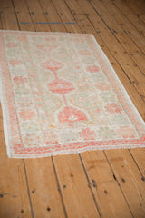 Angled perspective of a vintage Oushak rug showing its distressed low-pile and soft colors.