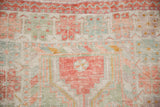 Hand-knotted texture showing mostly even wear on a distressed Oushak rug in pale red and green.