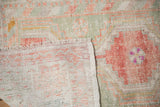 A corner of the vintage Oushak rug is folded, showing the hand-knotted foundation and the low pile.