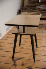 A vintage mid-century end table with two rectangular tiers and slender, dark tapered legs.