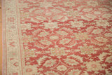 Distressed Oushak carpet detail: worn raspberry red, cream allover floral pattern, and border.