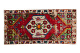 Vintage Oushak rug runner with a central shield medallion on a distressed cherry red field with floral accents.