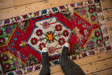 A person's overhead view of a distressed vintage Oushak rug runner with a colorful shield medallion.