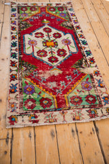 Worn cherry red and lime green pile on the corner of a vintage Turkish Oushak rug runner.