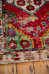 Textured wear on the hand-knotted pile of a vintage Oushak rug with colorful floral details.