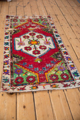 Angled view of a vintage Oushak runner with a cherry red field and vibrant geometric medallion.
