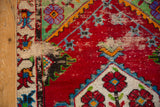 Corner detail of a vintage Oushak rug showing visible wear to the foundation and a machine bound edge.