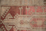 Vintage distressed Oushak rug section, abrash in blush red and beige, with ram's horn geometric motifs.