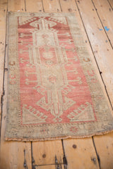 Machine bound corner of a distressed Oushak rug showcasing its pale raspberry and beige pile.