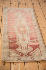 Vintage distressed Oushak rug border showing hook and latch motifs in pale raspberry and beige.