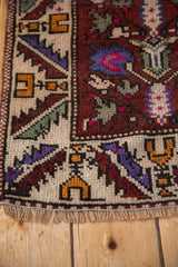 Corner detail of a hand-knotted Oushak rug showing its checkered and serrated leaf borders.