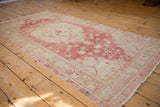 Angled view of a vintage Oushak runner highlighting its central medallion and soft raspberry and sand palette.