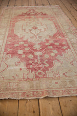Low-angle view of a distressed Oushak runner's raspberry red medallion and sand-colored field.