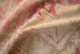 Detailed texture of a distressed Oushak rug showing worn knot heads in raspberry and sand.