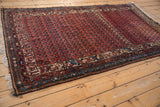 Antique Kurdish Hamadan rug close-up: dusty rose field, sapphire boteh patterns, and heavy abrash.