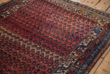 Antique Kurdish Hamadan rug's dusty rose field, repeating botehs, framed by a sapphire blue geometric border.