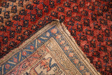 Antique Kurdish Hamadan rug folded corner, dense dusty rose pile, and woven ivory foundation with sapphire blue border.
