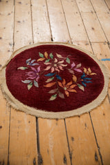 Angled view of the burgundy Art Deco round rug showing the scattered floral design.