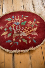 A vintage Art Deco round mat's textured pile, showing the central floral bouquet and even, time-softened wear.