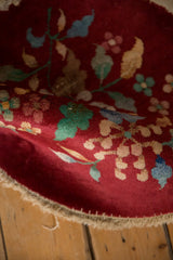 The curved edge of the burgundy Art Deco rug reveals its soft, even pile and floral design.