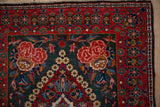 Rose design spandrel and cherry red floral border on a hand-knotted vintage Kashan rug.