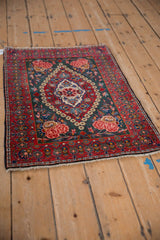 Vintage Persian Kashan rug from an angle, highlighting its concentric floral medallion and red border.
