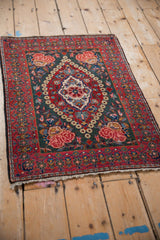 Angled view of the vintage Kashan rug, showing its traditional layout with a cherry red border and floral medallion.