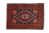Vintage fine Kashan rug with a floral medallion on a navy blue field and a rust-red border with rose spandrels.