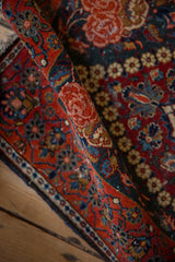 Texture detail of a vintage Kashan rug's low pile with cherry red and blue floral motifs.