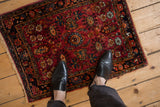 A vintage Lilihan rug with raspberry red and navy blue floral patterns shown for scale.