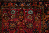 Detail of a vintage Lilihan's hand-knotted pile, showing floral sprays on a red field by a navy border.