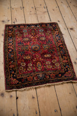 Vintage Lilihan rug with raspberry red and sapphire blue floral sprays, shown at an angle.