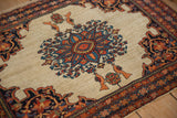 Low pile texture of an antique Farahan Sarouk rug's starburst medallion and perched bird motifs.