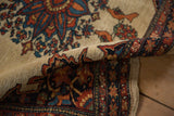 The folded corner of a collector's Farahan Sarouk rug shows bird motifs and its intricate serrated border.