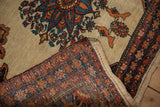 A folded corner of an antique Farahan Sarouk rug contrasts the intricate border with pictorial bird motifs.