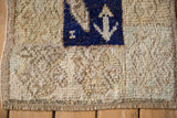 Distressed Tulu rug corner showing shaggy wool pile, exposed knot heads, and a cobalt blue motif.