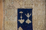 Germinating blossom motif in cobalt blue on the shaggy, distressed pile of a Tulu rug.
