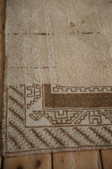 Intact side cord and geometric hook and latch border on a distressed beige Malatya rug.
