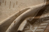 Folded corner of a distressed Turkish rug highlighting its even wear and geometric border motif.