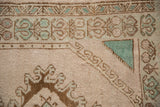 Corner detail of a vintage Oushak's prayer design with pale turquoise and bronze hook and latch motifs.