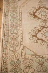 Vintage Oushak rug's geometric border showing evenly worn pile in muted turquoise and bronze tones.